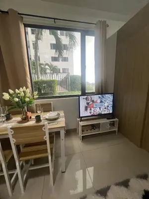 a living room with a table and a tv and a window at Seaside Serenity in Manila