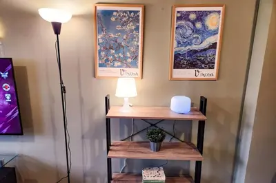 a table with a lamp and pictures on the wall at Artsy 110sqm 2br in MOA 200mbps Wifi XBOX Printer in Manila