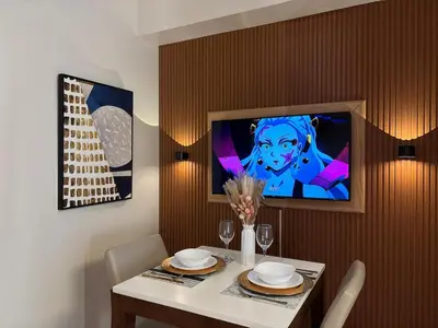 a dining room with a table and a tv on a wall at Cozy & Aesthetic 1 BR in BGC in Manila