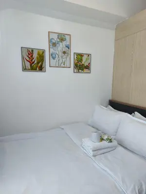 a bedroom with a white bed with three pictures on the wall at City Staycation Condo-SM Jazz in Manila