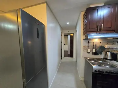 a kitchen with a stainless steel refrigerator and wooden cabinets at Central BGC - Spacious Modern 2 bedrooms 2 bathrooms with Balcony in Manila