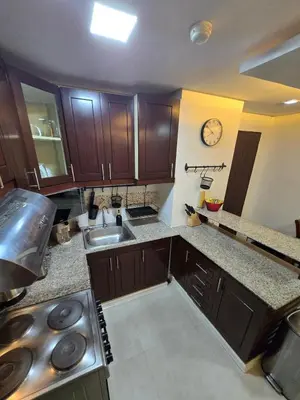 a kitchen with wooden cabinets and a clock on the wall at Central BGC - Spacious Modern 2 bedrooms 2 bathrooms with Balcony in Manila