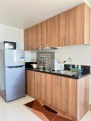 a kitchen with wooden cabinets and a stainless steel refrigerator at Shore 3 Tower 1 Condo staycation near MOA - DT in Manila