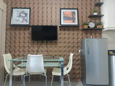 a dining room with a table and a television on a wall at Sea Reaidence Tower E in Manila