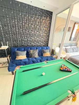 a living room with a pool table and a blue couch at Celestial Sphere Staycation at Azure Urban Resort Residences in Manila