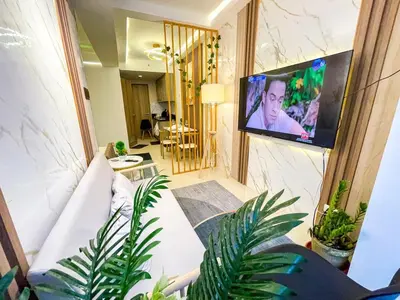 a living room with a white couch and a flat screen tv at Cozy & Chic 1BR near Mall of Asia - S Residences in Manila