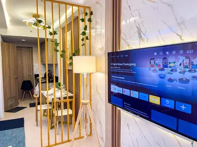 a television on a wall in a room with a table at Cozy & Chic 1BR near Mall of Asia - S Residences in Manila