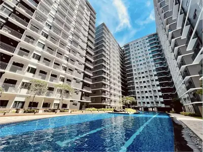 an apartment complex with a swimming pool in front of two tall buildings at MOA Staycation at Shore 3 Residences Tower 1 in Manila