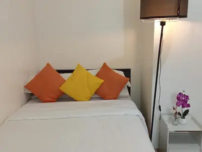 a bed with orange and yellow pillows on it at 2BR PIONEER Woodland Boni,Mandaluyong connected to Boni MRT station in Manila