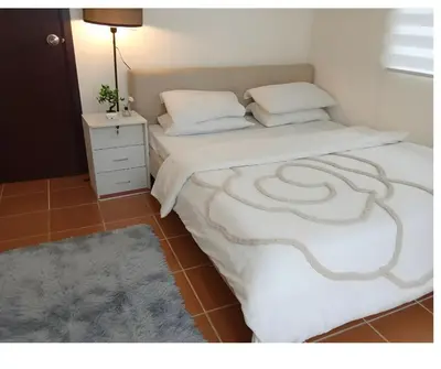 a bed with a white blanket and a night stand at 2BR PIONEER Woodland Boni,Mandaluyong connected to Boni MRT station in Manila
