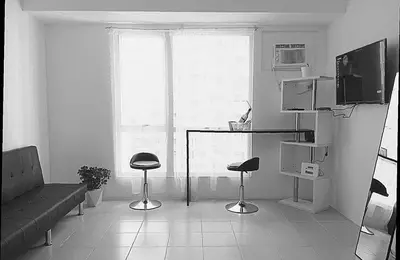 a living room with a couch and two stools in front of a window at 2BR PIONEER Woodland Boni,Mandaluyong connected to Boni MRT station in Manila