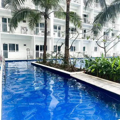 a swimming pool in front of a building with palm trees at Crizzy's Hub Gabrielle at Shore Residences in Manila