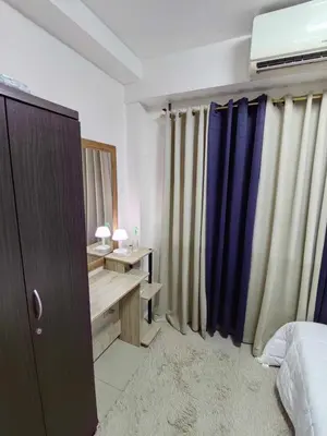 a bedroom with a bed and a desk and curtains at Mall of Asia's Staycation in Manila