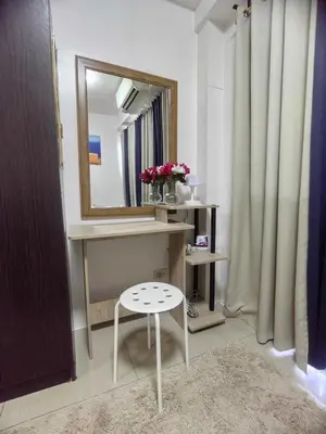 a bathroom with a vanity with a mirror and a stool at Mall of Asia's Staycation in Manila