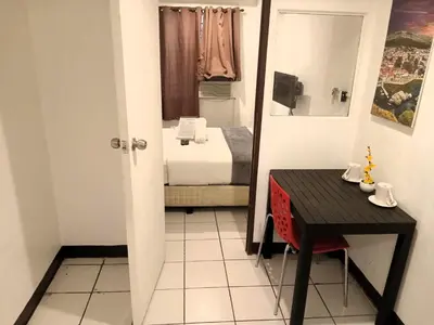 a small room with a bed and a table and a mirror at Circuit Suites in Manila