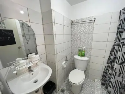 a white bathroom with a toilet and a sink at ADB Avenue Tower GOOD FOR 5 PAX in Manila