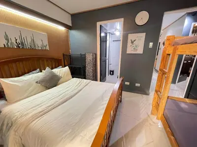 a bedroom with a large bed and a clock on the wall at 3 bedroom 89sqm midrise condotel in Manila
