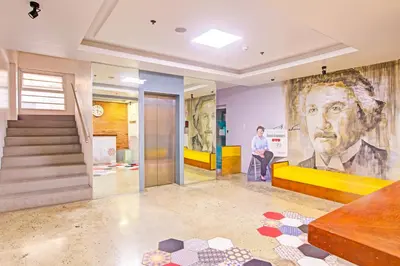 a woman standing in a lobby with a large painting of a man at Townhouse College Residences in University Belt, Metro Manila in Manila