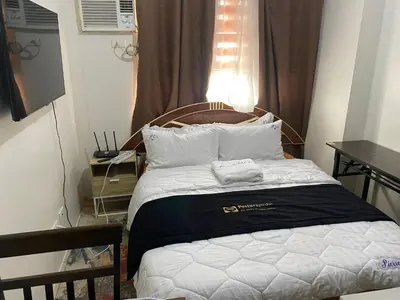 a bed with two towels on it in a room at Collins Condotel in Manila