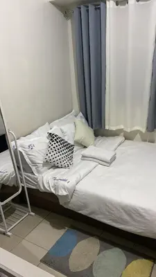 a unmade bed with a chair next to a window at Collins Condotel in Manila