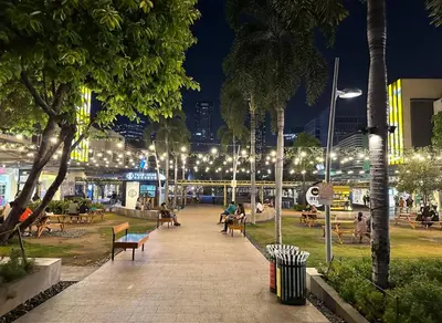 a park with people sitting on benches at night at 2BR in Central BGC in Manila