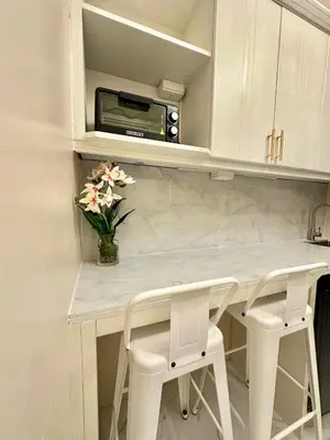a kitchen with a counter with two stools and a microwave at Studio Two Condominium, Alabang AMBER -Fiber WI-FI Netflix ready in Manila