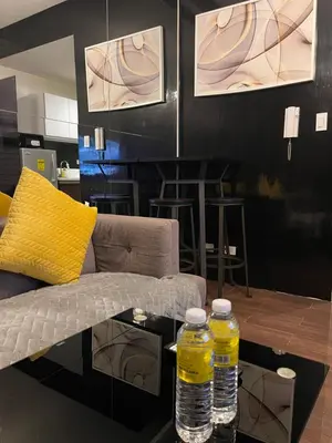two bottles of water sitting on a table next to a couch at Destina, 100Mbps at Air Residences, Makati, MetroManila, Netflix in Manila