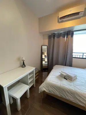 a bedroom with a bed and a desk and a window at Destina, 100Mbps at Air Residences, Makati, MetroManila, Netflix in Manila