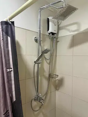a shower in a bathroom with a shower curtain at Stylish and Comfy Condominium in Manila