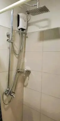 a shower in a bathroom with a soap dispenser on the wall at Stylish and Comfy Condominium in Manila