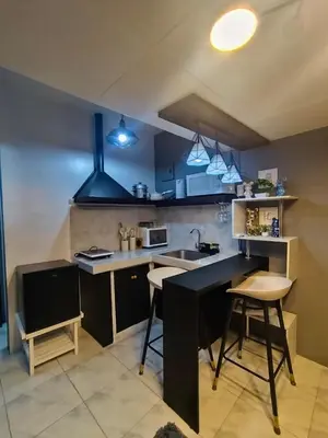 a kitchen with a sink and a counter with chairs at Cloves Den Binangonan Your Ultimate Cinema Date in Binangonan