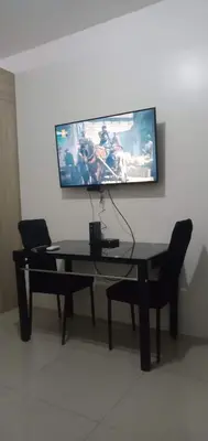 a table with two chairs and a tv on a wall at Shore 2 Staycation nice Homes in Manila
