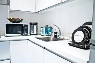 a white kitchen with a microwave and a sink at New York- Inspired Condo in Makati in Manila