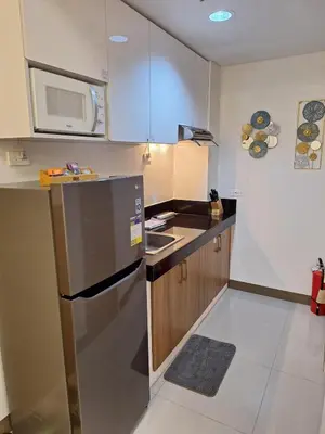 a small kitchen with a refrigerator and a microwave at 2BR Apartment plus FREE parking Near NAIA in Manila