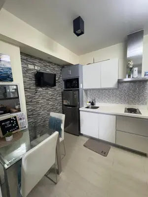 a kitchen with white cabinets and a stone wall at Miami 1909 in Manila