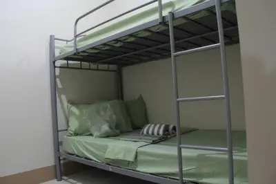 a bedroom with a bunk bed with green pillows at Cozy Urban Nest in Manila