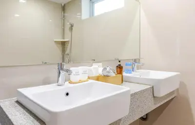 a white bathroom with two sinks and a mirror at BGC Taguig Uptown 3BR corner unit with pool view, bath tub, wifi, parking, beside Landers BGC in Manila