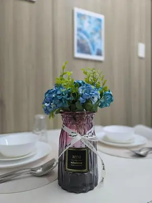 a vase with blue flowers sitting on a table at 1BR Solana Suite 5 at Coast Residences in Manila