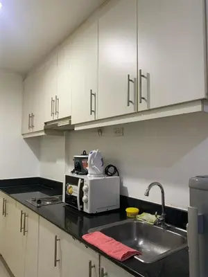 a kitchen with white cabinets and a sink and a microwave at Ballentos staycation in Manila