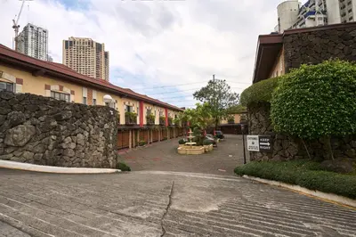 a building with a stone wall next to a street at Victoria Court Suites - Pasig in Manila