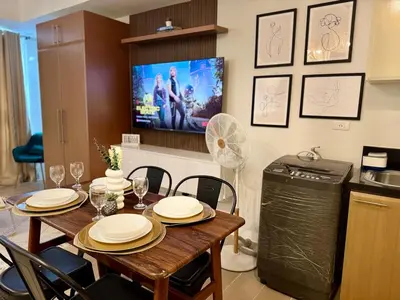 a dining room with a table and a tv at Cozy Staycation Venice with Balcony Mckinley near Bgc in Manila