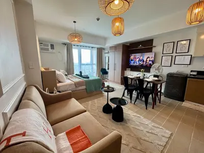 a living room with a couch and a dining room at Cozy Staycation Venice with Balcony Mckinley near Bgc in Manila