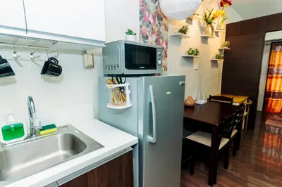 a kitchen with a sink and a refrigerator and a table at Chic Romantic Getaway Makati Studio One BR Two BR Swim Gym 300 MB in Manila