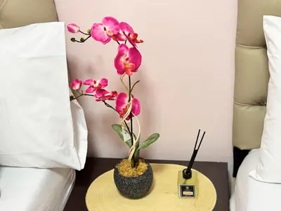 a nightstand with a table with a pink orchid on it at Grand Riviera Suites 1201 Near US Embassy and St Luke's Medical Center Extension Clinic SLEC by Prime Stay in Manila