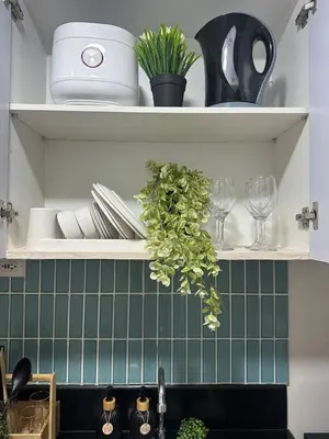 a kitchen shelf with plates and glasses and plants at Casa Alia at Coast - near MOA, US Embassy, PICC, WTC in Manila