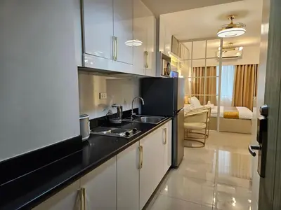 a kitchen with white cabinets and a black counter top at Luxury Condotel near MOA, NAIA in Manila