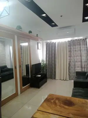 a living room with a couch and a television at 1633 pool view 2br in Manila