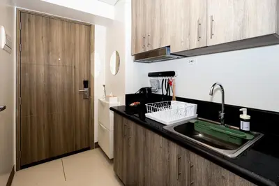a kitchen with a sink and a wooden door at Charlie's Staycation at Coast Residences in Manila