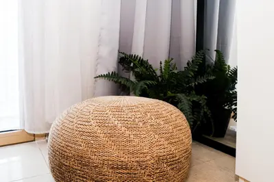a wicker stool in front of a window with plants at Charlie's Staycation at Coast Residences in Manila