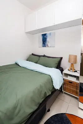 a bedroom with a bed with green sheets and a lamp at Charlie's Staycation at Coast Residences in Manila
